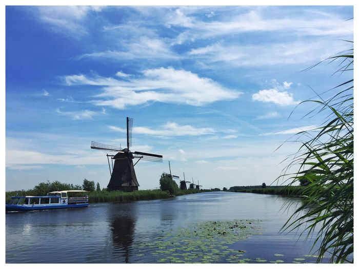 Traditional windmill by river against sky at kinderdijk