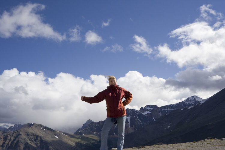 Low angle view of woman standing on whistler mountain against cloudy sky