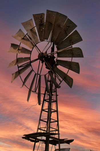 Low angle view of traditional windmill against sky during sunset