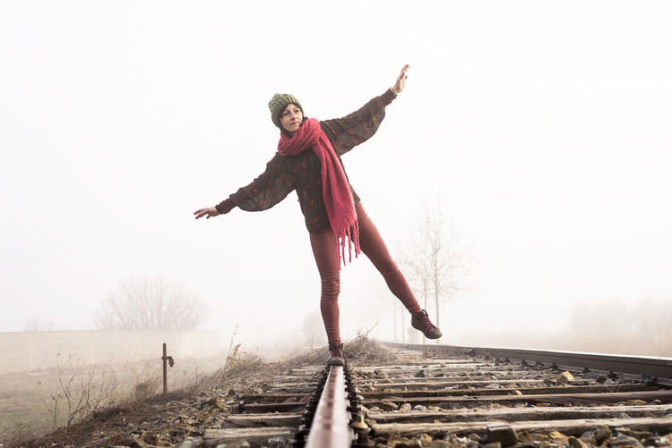 Full length of woman standing on railroad track against sky