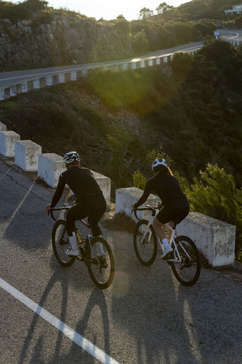 Man and woman cycling together on road, alicante, spain