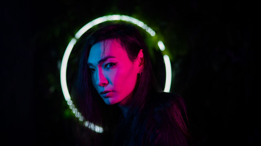 Portrait of asian man in hood in neon light. 