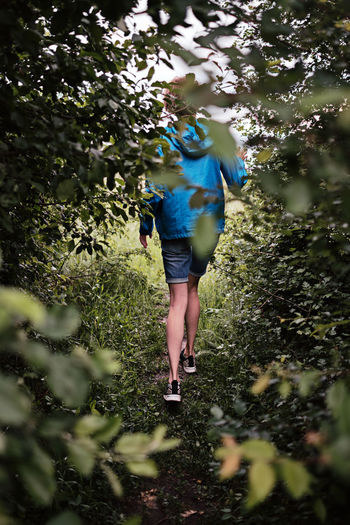 Rear view of woman running amidst plants