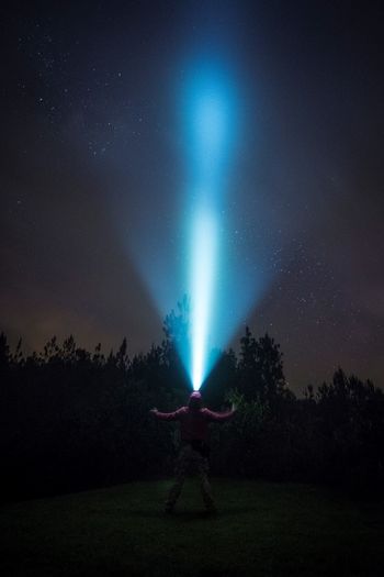 Man with illuminated headlamp standing against star field