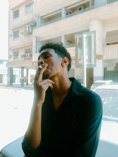 Young man while sitting in car and smokes a cigarette with the effect of a vintage old film camera 