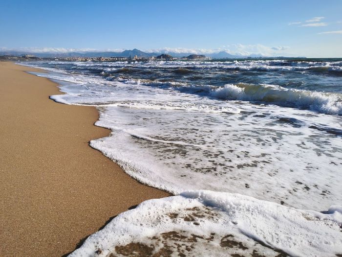 Waves rushing on shore against sky
