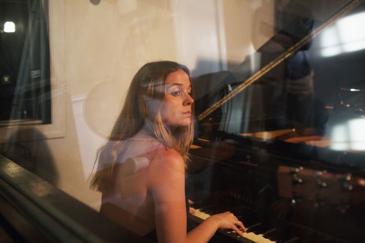 Young woman playing piano at a recording studio