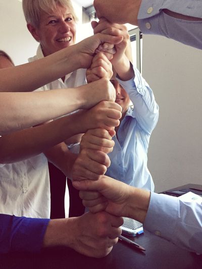 Happy business team making fist stack in office