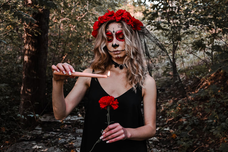 Happy halloween concept. scared horrible female in special outfit, wears white clay skull.