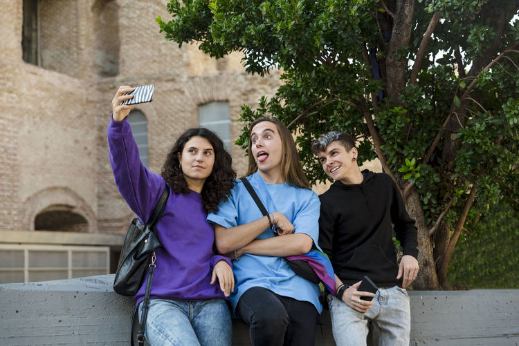 Young diverse friends taking selfie with a mobile phone outdoors.