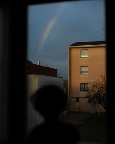 Silhouette of building against rainbow in sky