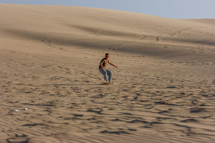 Man sandboarding at desert
