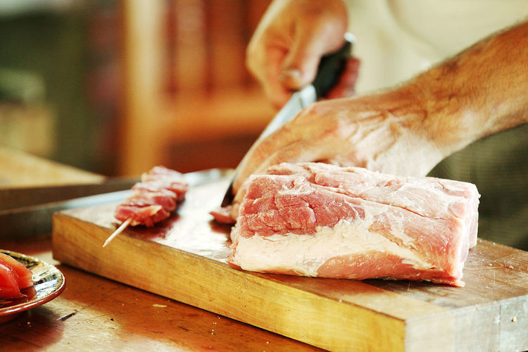 Cropped image of chef cutting meat