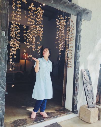 Full length of woman looking at dry plants hanging at home