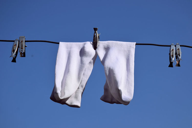 White socks hung on wire, blue sky in the background