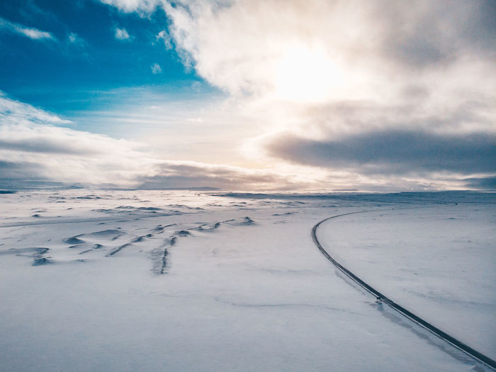 Snow covered landscape against sky during sunset