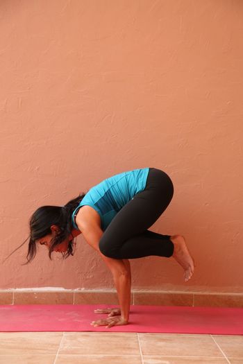 Young woman in crow pose by wall