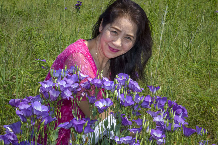 Portrait of woman on purple flowering plants on field