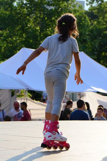 Rear view of girl roller skating on footpath