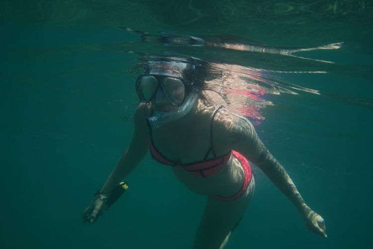 Woman wearing scuba mask while swimming in sea