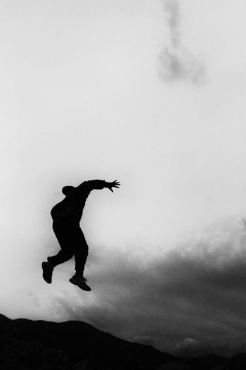 Silhouette of man jumping against sky