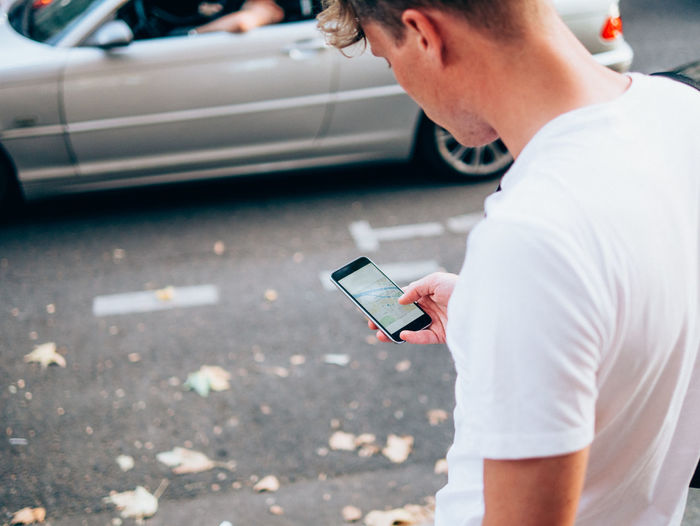 Rear view of man holding phone on street