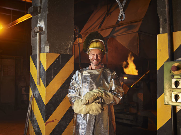 Smiling metal worker wearing protective workwear in steel mill