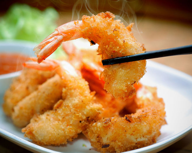 Close-up of fried prawn with chopsticks in plate