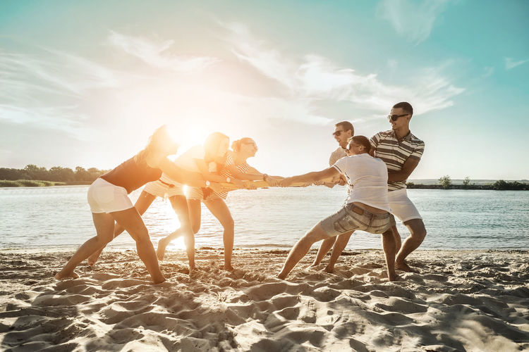 Happiness friends fun on beach under sunset sunlight in summer sunny day. funny group games.