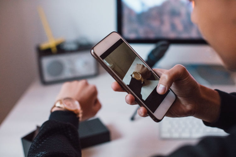 Cropped image of young blogger photographing hand with wristwatch at home