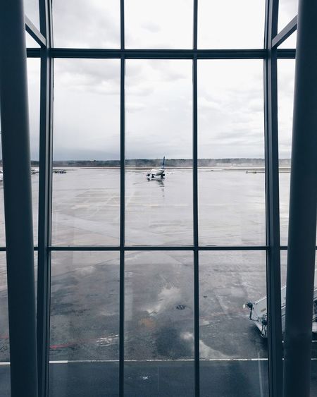 Airplane on airport runway seen through glass window