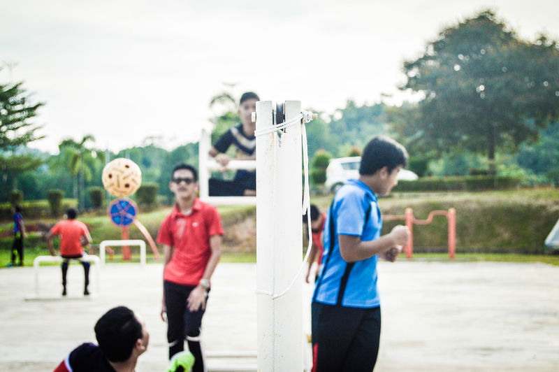 People playing soccer on field against sky