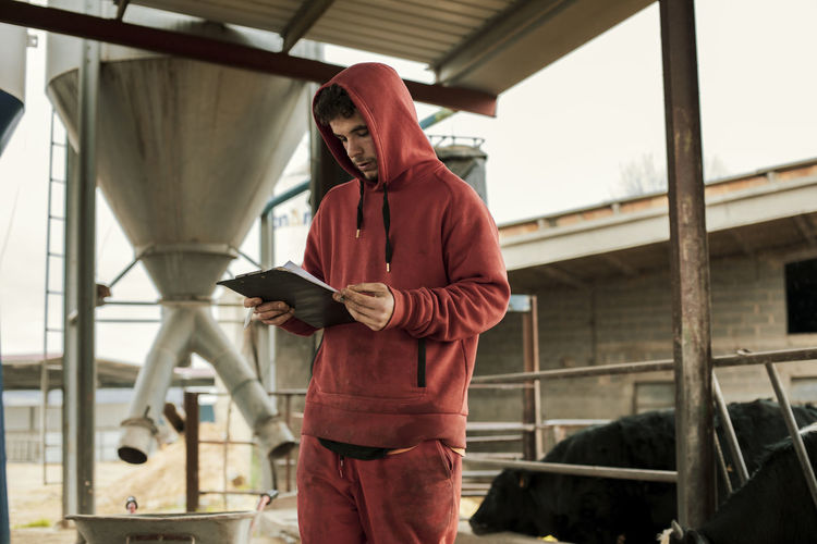 Farmer reading from clipboard while standing at ranch