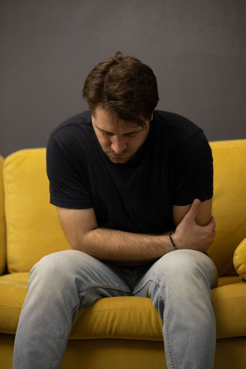Young man sitting on sofa at home