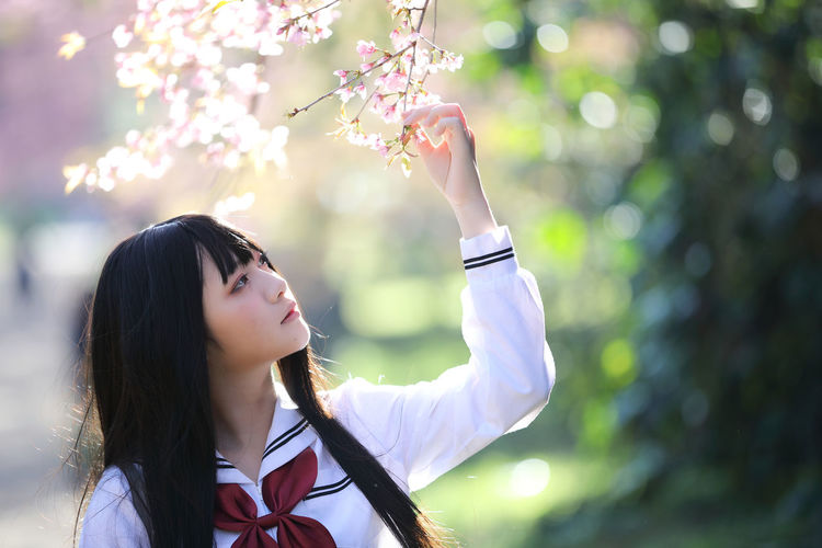 Young woman touching cherry tree outdoors
