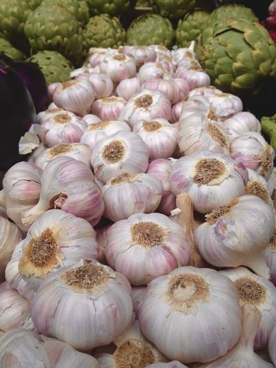 Close-up of garlic bulbs and artichokes for sale at market