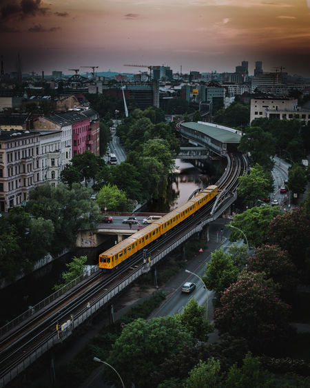 High angle view of train on railway bridge in city during sunset
