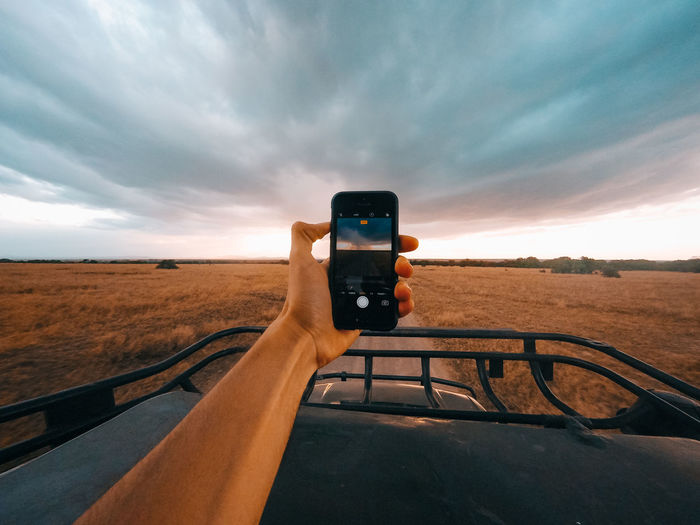 Man photographing on desert against sky