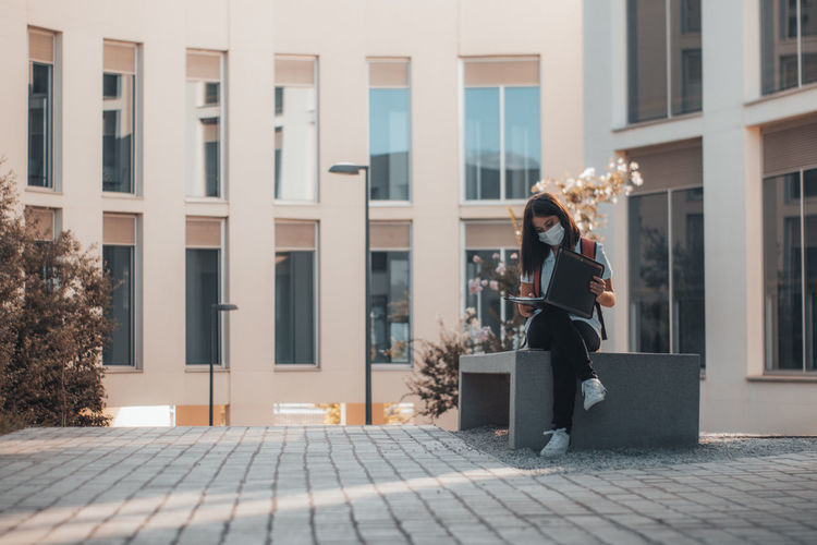 Side view of young man standing on street in city