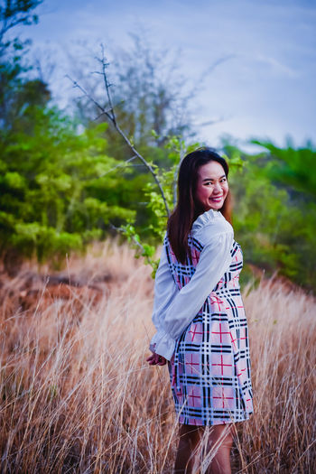 Portrait of smiling young woman standing on field
