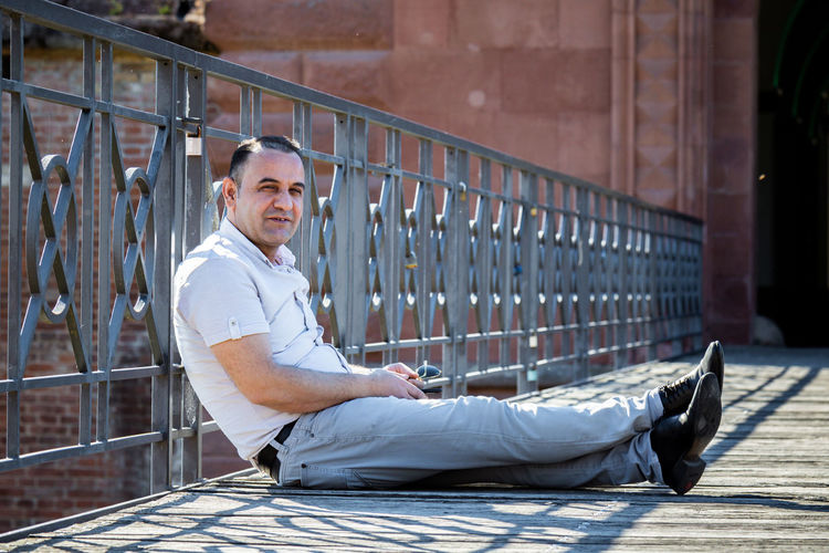 Portrait of man sitting on railing