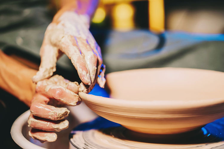 Cropped hands of potter making pot in pottery workshop