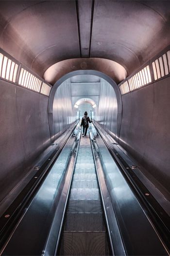 Rear view of woman standing on escalator