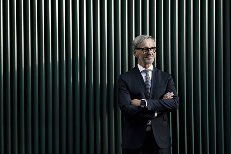 Portrait of businessman standing against wall