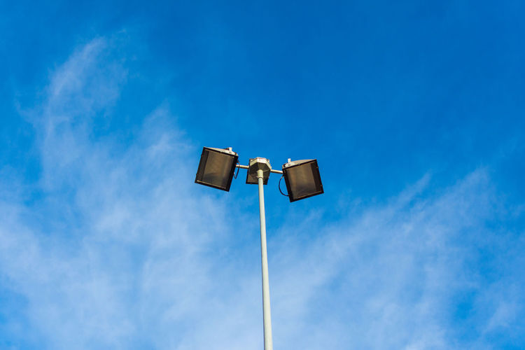 Low angle view of floodlights against blue sky