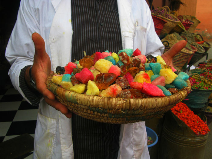Midsection of owner with colorful potpourri in basket at store