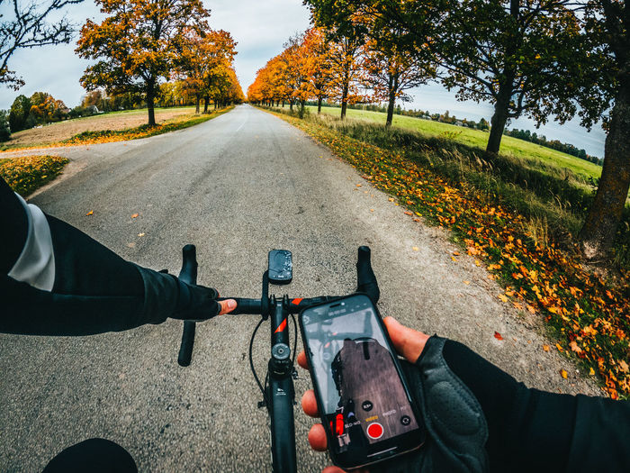 People riding bicycle on road amidst trees during autumn