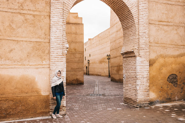Full length of woman standing against brick wall