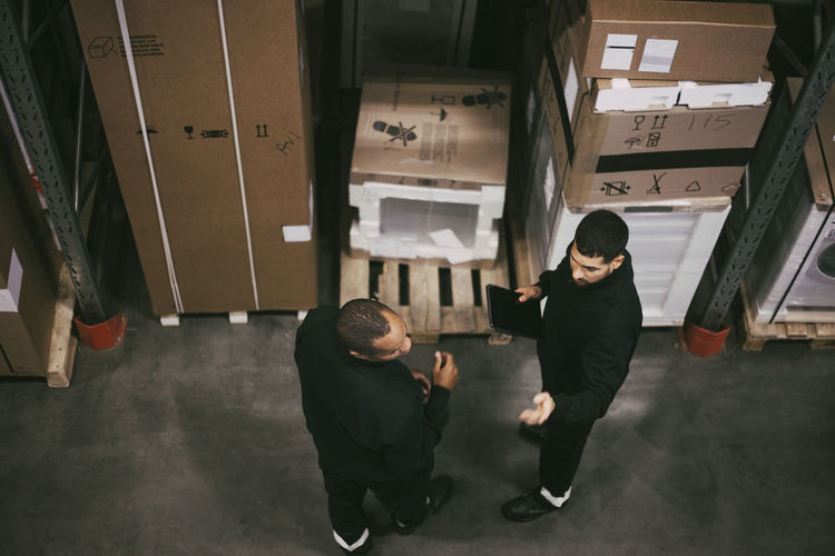 Businessman discussing with male colleague in logistics warehouse