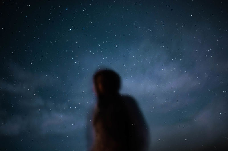 Defocused image of man standing against sky at night